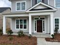 Inviting front porch with white columns and a dark wood front door, surrounded by manicured landscaping at 4038 Gardenia Dr # 0114, Harrisburg, NC 28075