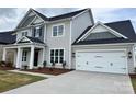 The home has an attached two-car garage with a concrete driveway, coach lights and a gray exterior at 4038 Gardenia Dr # 0114, Harrisburg, NC 28075