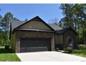 Charming single-story home with a black garage door and stone and siding details, surrounded by green trees at 6519 Pargo Rd, Charlotte, NC 28216