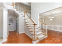 Grand foyer showcasing a staircase with wood railings and hardwood floors, leading to an open living space at 6941 Augustine Way, Charlotte, NC 28270