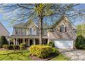 Inviting brick home with a covered porch, mature landscaping, and a two-car garage at 6941 Augustine Way, Charlotte, NC 28270