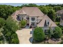 Elegant home with a combination of stone and stucco, complemented by mature landscaping and a circular driveway at 7409 Stonecroft Park Dr, Charlotte, NC 28226