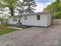 Single-story home with white siding, a metal roof, a rock driveway, and landscaping at 8475 Nc 49 N Hwy, Mount Pleasant, NC 28124