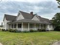 Charming two-story home featuring a wraparound porch and mature landscaping at 103 E Main St, Dallas, NC 28034