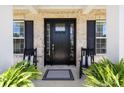 Inviting front porch with a stylish black door, rocking chairs, and lush ferns at 1052 Harlow'S Crossing Dr, Weddington, NC 28104