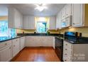 Well-lit kitchen featuring white cabinets, black countertops, and hardwood floors at 2540 Heritage Cir, Statesville, NC 28625