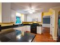 Cozy kitchen with white cabinets, black counters, and hardwood floors at 2540 Heritage Cir, Statesville, NC 28625