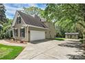 Side view of home featuring an attached two-car garage, shed, and wide driveway at 312 Peach St, Shelby, NC 28150