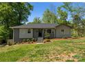 Charming single-story home with gray painted brick and siding, black front door, landscaped yard, and inviting curb appeal at 3423 Sudbury Rd, Charlotte, NC 28205