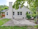 Back exterior with a brick chimney and a concrete patio, partially obscured by trees at 511 Hasty St, Marshville, NC 28103