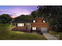 Charming brick home with a well-manicured lawn, attached garage, and inviting front porch under a dusky sky at 5301 Baker Dr, Charlotte, NC 28210