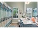 Bright bathroom with neutral walls, patterned shower curtain, single sink vanity, and a large window at 5927 Patricia Ryan Dr, Charlotte, NC 28216