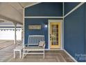Close up of a welcoming porch with a yellow door, bench, and charming decor at 63 Frost Ln, Taylorsville, NC 28681