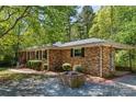Charming brick home featuring mature landscaping, quaint flowerbed, and an attached carport, all nestled in a peaceful setting at 6325 Elmwood Cir, Charlotte, NC 28214