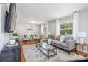 Bright living room featuring hardwood floors, a comfortable gray sofa, and large windows for natural light at 6325 Elmwood Cir, Charlotte, NC 28214