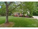 Landscaped front yard with a mature tree, colorful azaleas, and a well-maintained lawn leading to a brick home at 7206 Forrest Rader Dr, Mint Hill, NC 28227