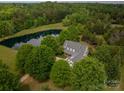 Aerial view of the property with mature trees and a large pond at 7701 Gold Hill Rd, Rockwell, NC 28138