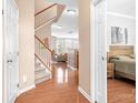 Inviting foyer features gleaming hardwood floors, elegant staircase, and access to bedroom at 11447 Potters Row, Cornelius, NC 28031