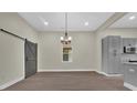 Bright dining area featuring a modern chandelier, sliding barn door, and sleek hardwood floors at 126 Hemphill Ave, Chester, SC 29706