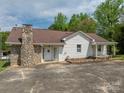 Charming single-Gathering home featuring a stone chimney, covered porch, and white vinyl siding at 1501 Nc Hwy 73 Hwy, Iron Station, NC 28080