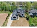 Aerial view of luxury home with dark roof on waterfront property surrounded by lush trees at 153 High Hills Dr, Mooresville, NC 28117