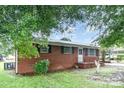 Attractive brick home featuring a covered front porch and well-manicured lawn at 2218 W Fifth Ave, Gastonia, NC 28052