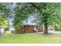 A classic brick home with a covered porch surrounded by lush greenery at 2218 W Fifth Ave, Gastonia, NC 28052