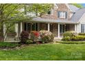 Charming home with a covered porch, colorful shrubs, lush lawn, and exterior stone accents at 263 Fernbrook Dr, Mooresville, NC 28117