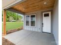 Covered porch features a wood ceiling, a white front door with glass inserts, and a view of the green lawn at 28655-A Nc Hwy 73 Hwy, Albemarle, NC 28001