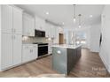 Bright, contemporary kitchen featuring white cabinets, stainless appliances, a large island, and modern pendant lighting at 433 Blairhill Rd # 08, Charlotte, NC 28217