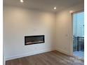 Bright living room featuring a modern electric fireplace, hardwood flooring, neutral walls and a sliding door leading to outdoor space at 433 Blairhill Rd # 08, Charlotte, NC 28217