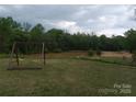 Tranquil pond with swing set, surrounded by lush greenery and mature trees at 4330 Goodman Lake Rd, Salisbury, NC 28146