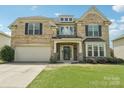Inviting two-story brick home featuring a manicured lawn, a covered porch, and an attached garage at 5037 Nighthawk Dr, Fort Mill, SC 29707