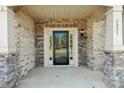 Close-up of a covered front porch with brick and stone accents and a black-framed glass door at 5037 Nighthawk Dr, Fort Mill, SC 29707