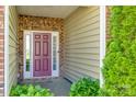 Inviting front porch with a brick facade, colorful door, and lush greenery at 5050 Kinross Ln, Indian Land, SC 29707