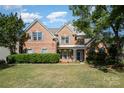 Attractive brick home featuring a manicured front lawn, inviting entrance, and lovely landscaping at 6904 Mordred Ln, Charlotte, NC 28277