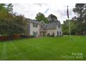 A well-maintained home features a lush green lawn, mature trees, and classic architectural details at 9106 Dogwood Ridge Dr, Charlotte, NC 28227