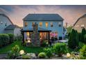 Backyard view of a two-story home with a cozy covered patio, stone fireplace, and outdoor seating at 2002 Thurston Dr, Indian Trail, NC 28079