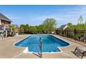 Sparkling in-ground pool surrounded by a secure fence, set against a backdrop of mature trees and manicured lawns at 2610 Flagstone Ct, Shelby, NC 28152