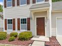 Exterior shot of the home's entry, showcasing a brown front door with manicured landscaping at 303 Landis Oak Way, Landis, NC 28088