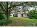The house boasts a well-maintained lawn, and blue shutters enhancing the curb appeal, nestled under a large tree canopy at 3606 White Swan Ct, Indian Trail, NC 28079
