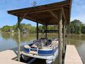 Covered boat dock features a blue pontoon on a lake with treelined backdrop and sunny sky at 6778 Emerald Isle Dr, Sherrills Ford, NC 28673