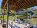 Docked pontoon boat in covered shelter shows seating, console, and sunshade for a fun day on the lake at 6778 Emerald Isle Dr, Sherrills Ford, NC 28673