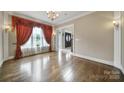 Bright living room featuring hardwood floors, large window with decorative curtains, and an open doorway at 802 Capington Ln, Waxhaw, NC 28173