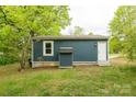 Exterior view of single-story blue home showcasing the side entry door and a small storage shed at 1011 Rickert St, Statesville, NC 28677