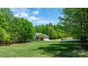 Spacious front yard featuring a brick house, a long driveway, and surrounding mature trees at 1590 W 7Th St, Newton, NC 28658