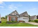 Inviting one-story home featuring a brick and siding facade, lush lawn, and convenient two-car garage at 20135 Dovekie Ln, Fort Mill, SC 29707