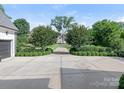 Long concrete driveway leading to a beautiful home, framed by trimmed shrubs and mature trees at 2343 Vernon Dr, Charlotte, NC 28211