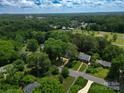 Wide aerial shot of a home with green lawns surrounded by mature trees and a blue sky at 2601 Pinewood Rd, Gastonia, NC 28054