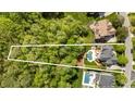 An aerial view showcases lush wooded property with home and pool outlined in a bright white line at 3306 Delamere Dr, Matthews, NC 28104